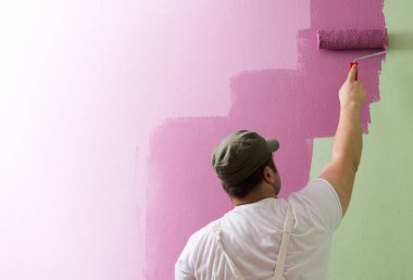 Genç adam boyama duvar boyama rulo olduğunu