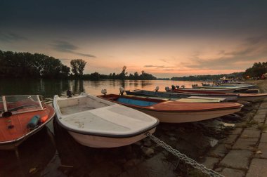 Gün batımında nehir kıyısında bağlantılı tekneler