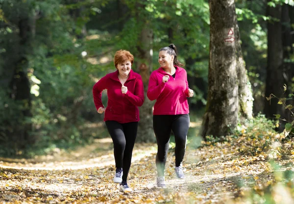 母亲和女儿穿着运动服在山上的森林里奔跑 — 图库照片