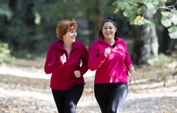 Mother and daughter wearing sportswear and running in forest at mountain