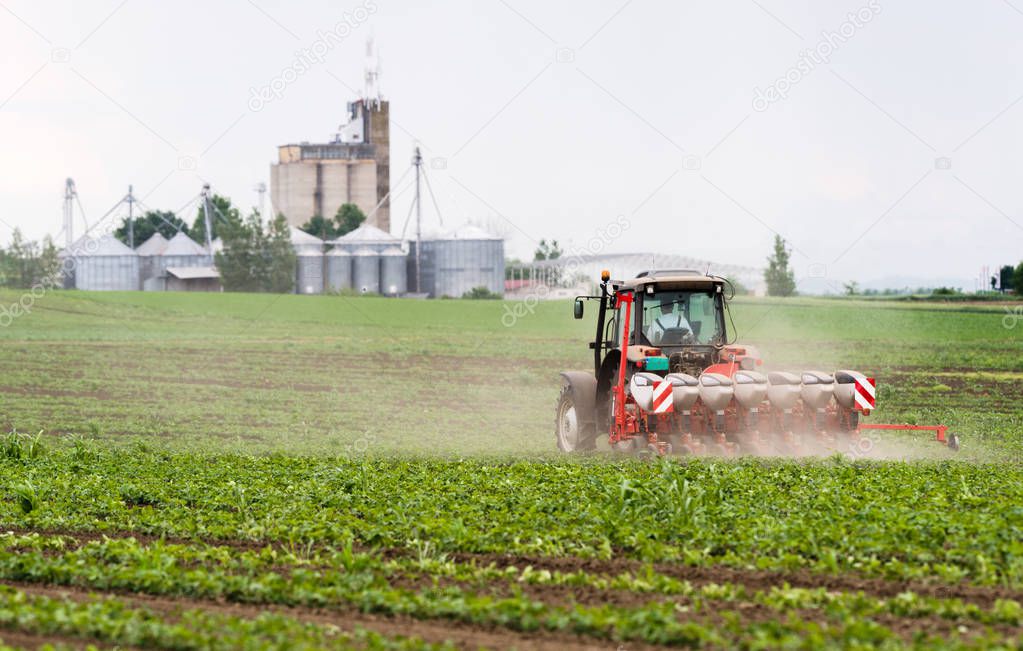  Farmer with tractor seeding  crops at agricultural field