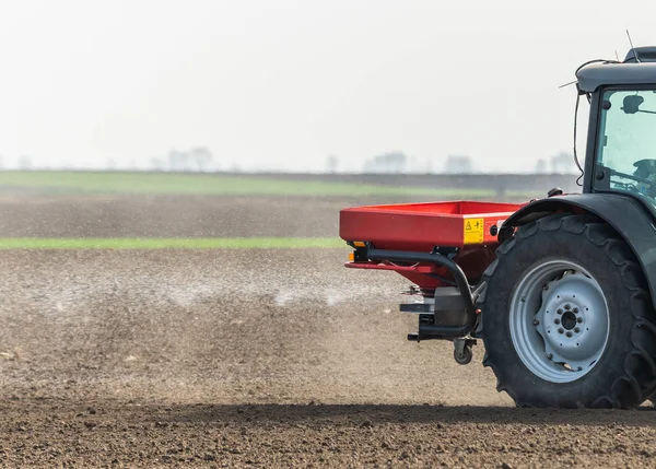 Tractor spreading artificial fertilizers in field — Stock Photo, Image