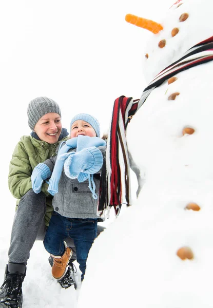 Smiling baby boy and his mother building snowman — Stock Photo, Image