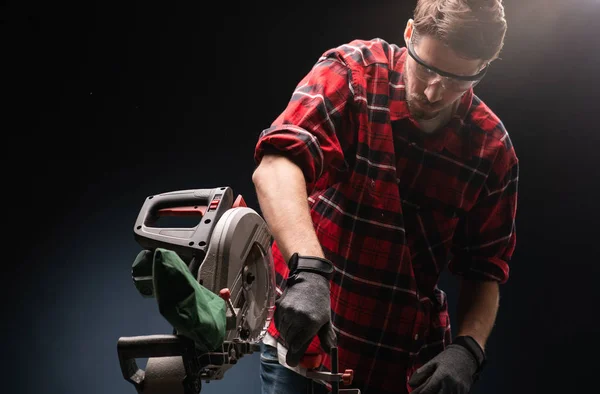 Beau homme utilisant une scie circulaire électrique moderne dans l'atelier — Photo