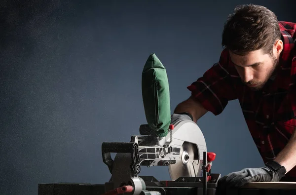 Beau homme utilisant une scie circulaire électrique moderne dans l'atelier — Photo