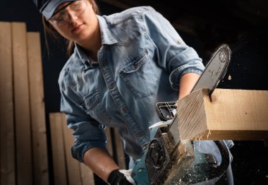 Atölyede modern elektrikli testere kullanan genç kadın