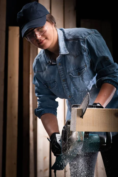 Jonge vrouw met behulp van moderne elektrische zaag in de workshop — Stockfoto