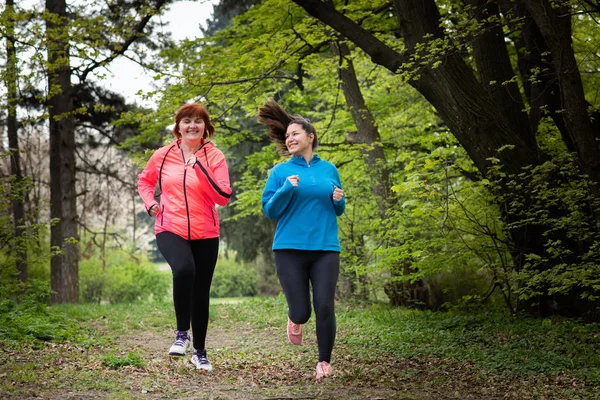 Madre e hija usando ropa deportiva y corriendo en el bosque — Foto de Stock