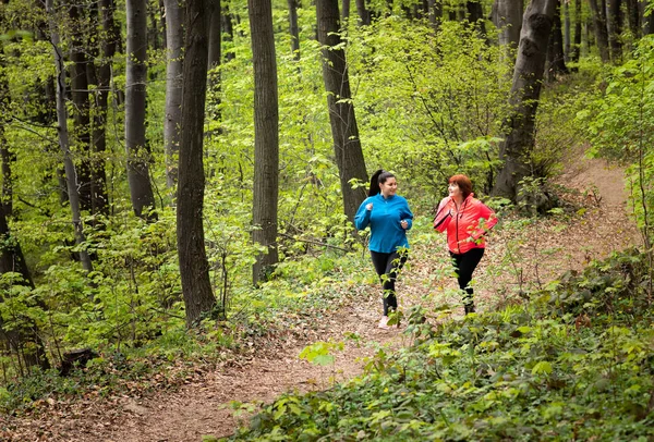 Madre e figlia indossano abbigliamento sportivo e corrono nella foresta — Foto Stock