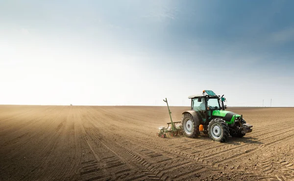 Agricultor con siembra de tractores sembrando cultivos en el campo agrícola — Foto de Stock
