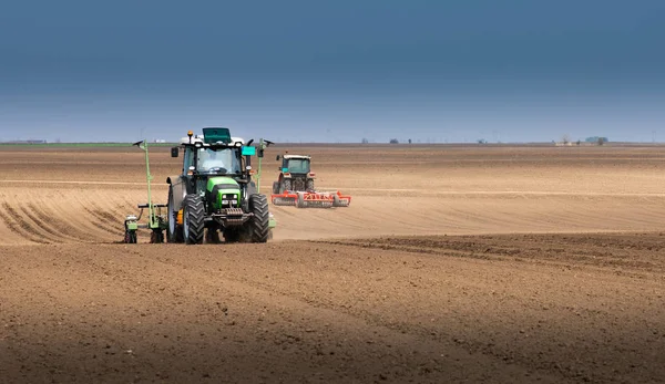 Agricultor con siembra de tractores sembrando cultivos en el campo agrícola — Foto de Stock