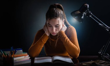 Genç, güzel ama stresli öğrenci kız zor sınava çalışıyor.