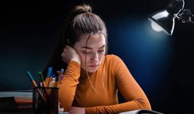 Genç, güzel ama stresli öğrenci kız zor sınava çalışıyor.