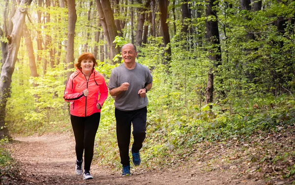 Husbanf and wife wearing sportswear and running in forest — Stock Photo, Image