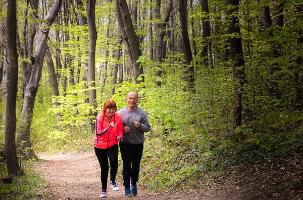 Husbanf a manželka nosí sportovní oblečení a běží v lese — Stock fotografie