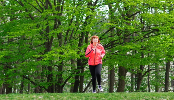 Középkorú womn visel sportruházat és futás erdőben — Stock Fotó