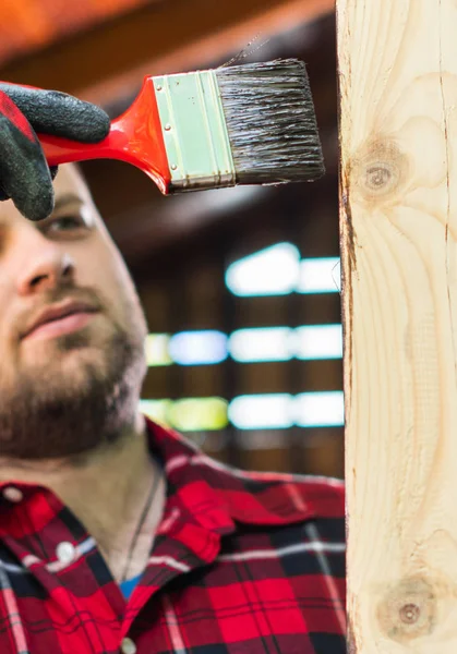 Młody człowiek maluje drewnianą powierzchnię pędzlem — Zdjęcie stockowe