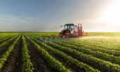 Traktor rozprašuje pesticidy na sójové pole postřikovačem na jaře