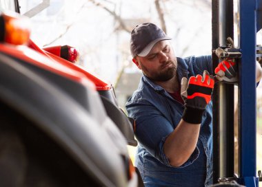 Çiftçi tarladaki tarım makinelerini tamir ediyor. 
