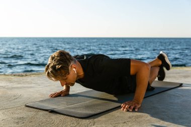 Yetişkin sporcu gönderme yapıyor radyo earphones ile ups üzerinde deniz kıyısı
