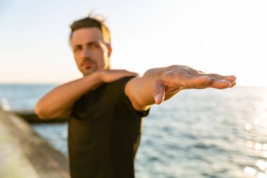 yakın çekim yetişkin sporcu germe kolun sahil eğitim önce vurdu