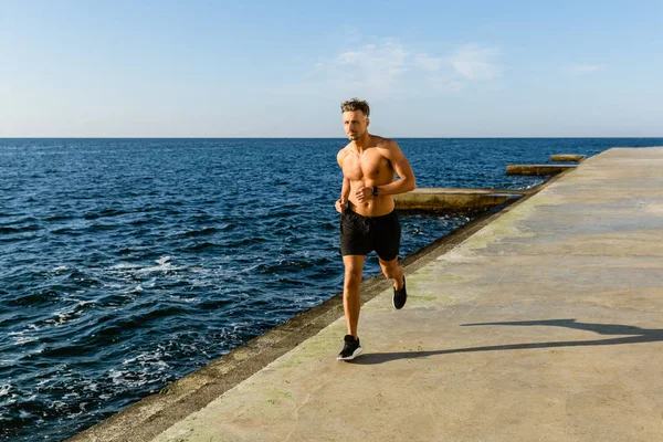 运动成人无上衣男子在海滨慢跑 — 图库照片