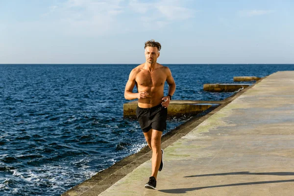 Muscular Shirtless Sportsman Jogging Seashore — Stock Photo, Image