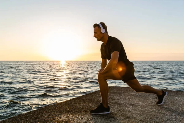 Athletic Adult Man Headphones Doing One Legged Squats Training Seashore — Stock Photo, Image