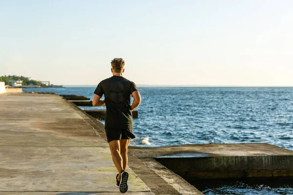 Красивий дорослий спортсмен біжить на березі моря — стокове фото
