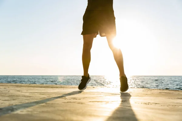 Handsome adult sportsman jumping on seashore — Stock Photo