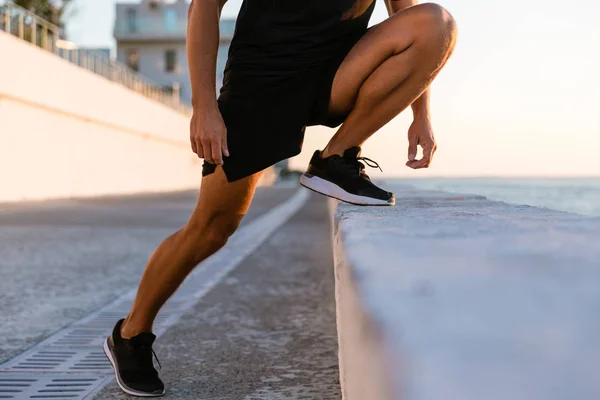 Schnappschuss eines Sportlers, der sich vor dem Training am Strand dehnt — Stockfoto