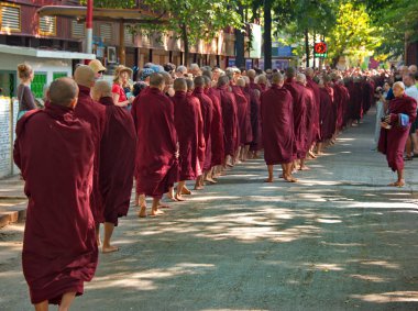 Mandalay. Myanmar. 11/21/2016. Çok sayıda turist le çevrili genç Budist rahipler, her sabah erken saatlerde namazdan sonra yiyecek için gemilerle kahvaltı için sıraya giriyor..