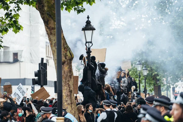 Londra / İngiltere - 06 / 06 / 2020: Siyahi Yaşamı Önemlidir protestosu koronavirüs salgını sırasında. Başbakanlık binasında pankartlı protestocular, dumanlı granadesm pankartları