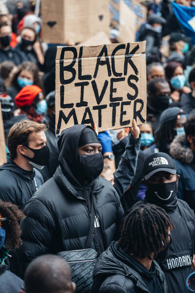 Лондон / Великобритания - 06 / 06 / 2020: Black Lives Matter protest during lockdown coronavirus pandemic. Протестующий держит баннер BLM на Вестминстерской площади
