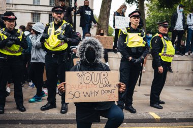 London / UK - 06 / 07 / 2020: Black Lives Matter protestosu koronavirüs salgını sırasında gerçekleşti. Başbakanlık binasında polisin önünde bayrak sallayan protestocu.