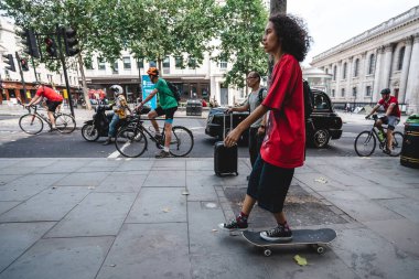 Londra / İngiltere - 08 / 09 / 2020: Londra 'nın orta kesiminde kırmızı tişörtlü genç adam kayıyor