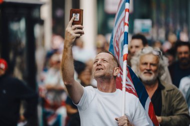 Londra, Birleşik Krallık 2025.09.13 Bir protestocu Londra 'nın merkezinde büyük bir kalabalık tarafından çevrelenmiş ifade özgürlüğü gösterisine katılırken telefonunu kaldırır ve bir bayrak tutar.. 