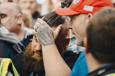 Londra, Birleşik Krallık 2025.09.13 Bir protestocu başını dövmeli bir elle kapatırken, kırmızı şapkalı başka bir adam konuşma özgürlüğü mitinginde onunla konuşuyor. Sahne, yoğun ve saf duyguları yakalar.. 