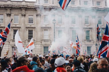 Londra, Birleşik Krallık 2025.09.13 Protestocular, arkasında duman yükselen Özgür Konuşma protestosu sırasında tarihi bir binanın önünde Jack ve St. George bayraklarını sallıyor.. 
