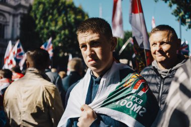 Londra, Birleşik Krallık 2025.09.13 Westminster 'da düzenlenen Özgür Konuşma protestosu sırasında bayraklara sarılmış genç bir gösterici arka planda Union Jack ve St. Georges bayraklarıyla birlikte kalabalığın arasında duruyor.. 