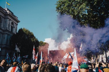 Londra, Birleşik Krallık 2025.09.13 Protestocular Westminster 'da düzenlenen Özgür Konuşma Yürüyüşü sırasında havayı dumanla dolduran Union Jack ve St. Georges bayraklarını sallıyorlar. Büyük bir ekran ve Ukrayna bayrağı görünür. 