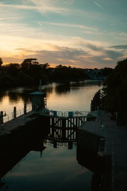 Londra, Birleşik Krallık 2025.09.06 Richmond Lock ve Weir on the River Thames gün batımında, yumuşak akşam ışığı yansıyan su ve sıcak renklerde bulutlar. 