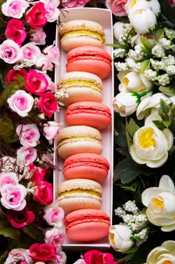 Üstten görünüm üzerinde bir hediye kutusu ve çiçek renkli macaroons.