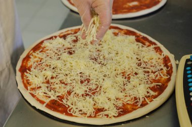 Domates sosu pizza tabanı üzerinde yayıldığını peynir