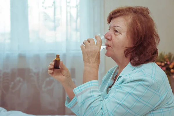 Senior woman drink medicine in bed. — Stock Photo, Image