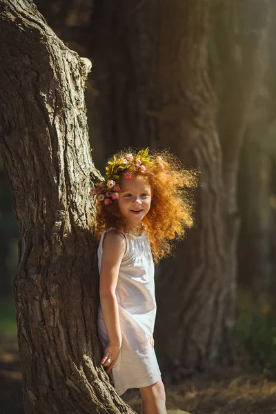 Kırmızı saçlı kız çiçeklerle ormana yürüme.