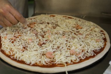 Şef karides ve peynirli pizza pişiriyor..