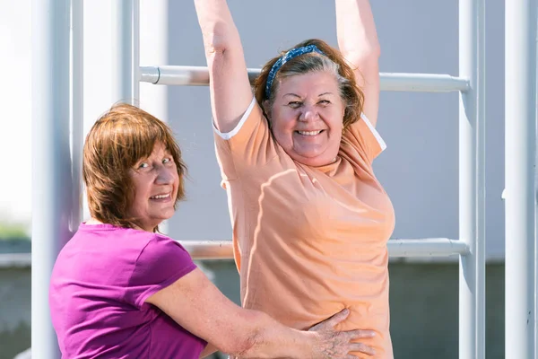 Dos mujeres mayores practicando fitness en el campo de deportes exterior . — Foto de Stock