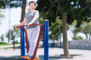 Spor sahasında spor yapan yaşlı bir kadın. Emekli insanlar için sağlıklı bir yaşam tarzı.