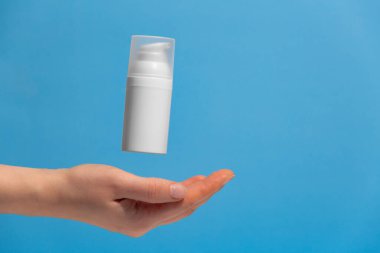 Uçan kozmetik ürünü markasız bir kadın eli, yazı için boş yer. Güneş kremi nemlendiricisi reklamı yapıyorum..